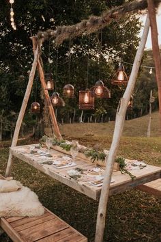 a wooden swing bed with lights hanging from it's sides and pillows on the ground