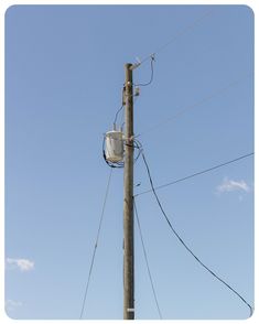 an electric pole with power lines and wires attached to it, against a blue sky