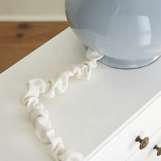 a blue vase sitting on top of a white dresser next to two metal knobs