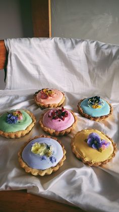 six decorated cookies sitting on top of a white sheet