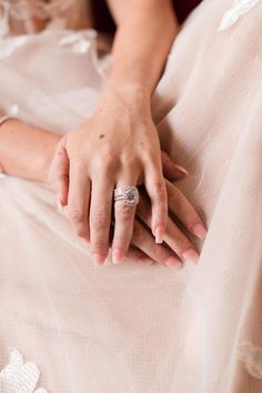 a close up of a person's hand with a ring on their finger and wedding dress