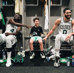 two men and a young boy sitting in a locker room with basketball gear on the floor