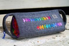 a gray bag with multicolored arrows on it sitting on top of a rock