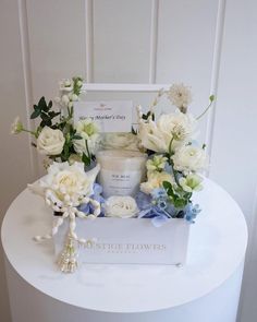 a white box filled with flowers sitting on top of a table next to a candle