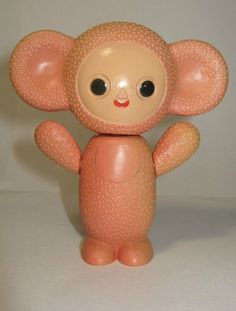 a small pink toy with big eyes and an elephant like body, standing upright on a white surface