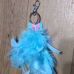 a blue feather keychain with a pink butterfly on the front and back side