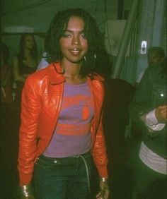 a woman wearing a red leather jacket standing in front of a group of other people