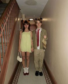 two people dressed up in costumes standing on the hallway with one holding a teddy bear