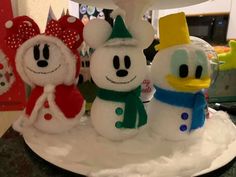 three snowmen with hats and scarves on top of a table