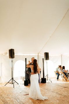 a bride and groom are dancing in a tent