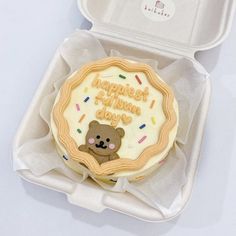 an open box with a decorated cookie in the shape of a teddy bear on it