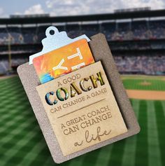 a close up of a coach's name tag on a baseball field with a stadium in the background