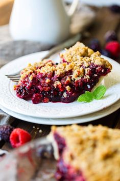 a piece of pie on a white plate with raspberry sauce and fresh berries