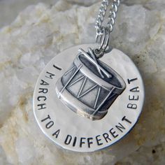 a silver necklace with a drum on it that says, i am march to a different beat