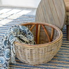 a wicker basket sitting on top of a rug next to a wooden table and chair