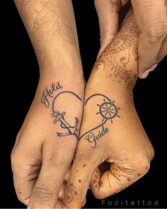 two people holding hands with tattoos on them