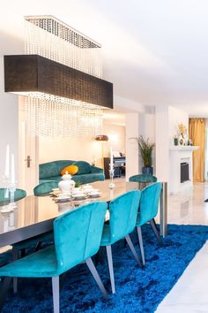 a dining room table with blue chairs and a white rug on the floor in front of it