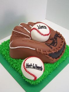 two baseballs and a mitt on top of green grass with white walls in the background