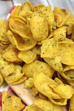 a pile of cheesy potato chips sitting on top of a wooden cutting board