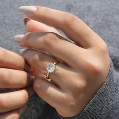 a woman's hand holding an engagement ring with a white diamond in the middle