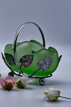 a green glass vase sitting on top of a table next to some white and pink flowers