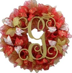 a red and gold mesh wreath with the letter g on it's front door