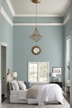 a bedroom with blue walls, white bedding and a chandelier hanging from the ceiling