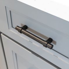 an image of a kitchen cabinet door handle on the front of a white cupboard with black handles