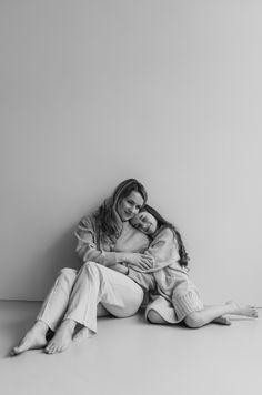 black and white photo of two women sitting on the floor hugging each other with their arms around one another