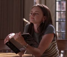 a woman sitting at a table reading a book