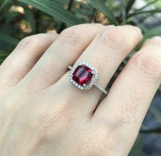 "A stunning princess-shape faceted 1ct lab-made Ruby accented with a halo of petite cubic zirconia is a lovely engagement/promise/anniversary ring handcrafted in sterling silver. Wrapped in a box ready for gift-giving. (r-egt-126-lab ruby) Ring Info -------------------------- Lab Ruby 6mm, 1ct Lab Ruby with Halo measure 9mm Shank width 1.5mm Stone height 7mm ----> Please note there is an additional fee, if we have to size the ring again so please make sure you know your ring size. ---> Don Halo Engagement Ring Square, Ruby Promise Ring, Square Halo Engagement Rings, Rubin Ring, July Birthstone Ring, Round Halo, Promise Rings For Her, Red Gemstones, July Birthstone