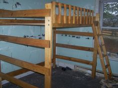 a wooden bunk bed sitting inside of a room next to a window with no curtains