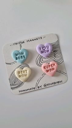 three heart shaped magnets on top of a white plate with words that say mom and best mom