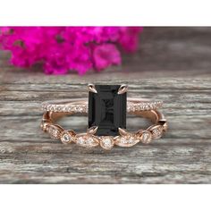 a black and white diamond ring on top of a wooden table with pink flowers in the background