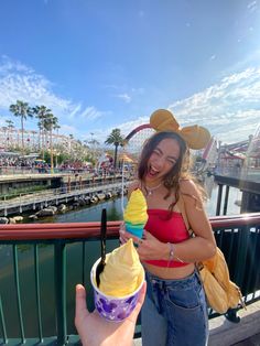 a woman holding an ice cream cone in her right hand and smiling at the camera