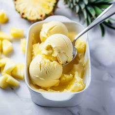 two scoops of ice cream in a white container with pineapple slices around it