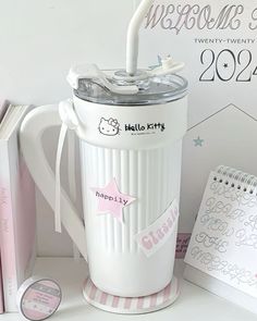 a white coffee mug sitting on top of a table next to books and notebooks