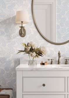 a bathroom vanity with a mirror above it and flowers in a vase on the counter