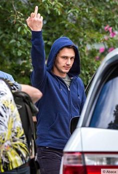 a man in a blue hoodie waves to the crowd