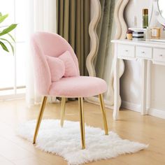 a pink chair sitting on top of a wooden floor next to a white table with a mirror