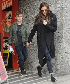 a woman and a boy are walking down the street holding hands as they hold hands