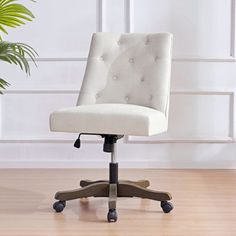 a white office chair sitting on top of a wooden floor next to a potted plant