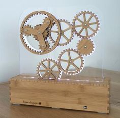 three wooden gears in a clear case on top of a wood table with a white background