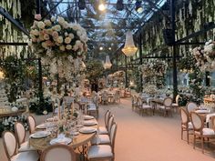 an indoor wedding venue set up with tables, chairs and chandeliers decorated with flowers