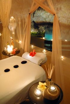 a spa room with candles and towels on the bed