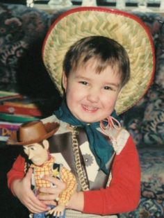 a young boy wearing a cowboy hat and holding a stuffed animal