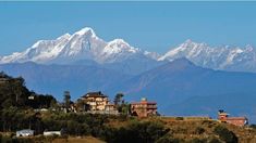 the mountains are covered with snow in the distance, and houses on the hillside below