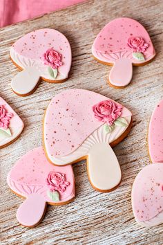 decorated cookies with pink frosting and flowers on them sitting on a wooden table top