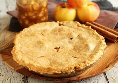 an apple pie on a wooden plate with cinnamon sticks