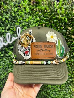 a person holding up a green hat with a tiger on it and the words, tree hugs birthday don't touch me